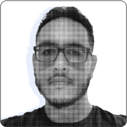 A imagem mostra um homem de barba curta, cabelos curtos e óculos, com expressão neutra. A foto é em preto e branco, tem efeito pixelizado e fundo claro.